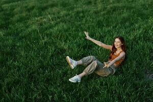 un' giovane donna è giocando nel il parco con noi nel il erba e cascate per il terra sorridente felicemente nel il luce del sole. riposo nel natura, armonia con il corpo foto