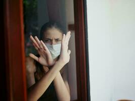 femmina medico maschera attraversato sua braccia nel davanti di sua nel il bandire finestra foto