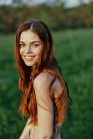 un' bellissimo dai capelli rossi donna ride e sorrisi con sua denti nel il luminosa tramonto luce del sole. il concetto di salutare vivente e bene nutrizione foto