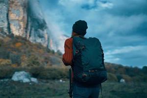 viaggiatore nel un' maglione con un' zaino su sua indietro turismo nuvole cielo paesaggio foto