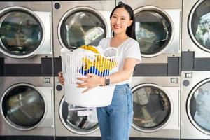 asiatico bellissimo donna sorridente contento fare faccende a il lavanderia foto