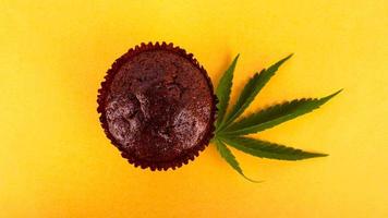 torta di muffin al cioccolato con marijuana su sfondo giallo foto