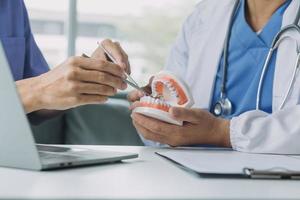 i dentisti stanno discutendo di problemi dentali per segnalare ai pazienti l'immagine a raggi X sullo schermo del laptop. foto