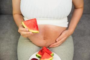 donna incinta mangia frutta anguria mela uva foto