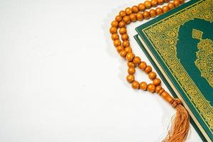 il santo al Corano con scritto Arabo calligrafia senso di al Corano e rosario perline o tasbih su bianca sfondo con copia spazio. foto