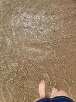 donna di piedi immersa nel il mare acqua a il spiaggia su un' soleggiato caldo giorno foto