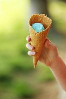 mano femminile che tiene il cono di cialda con gelato blu. primo piano, prodotto ad alta risoluzione. gelato blu in mano