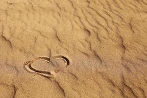 cuore disegnato sulla sabbia, concetto di amore. rilassarsi sulla spiaggia di sabbia. copia spazio. San Valentino su una spiaggia assolata foto