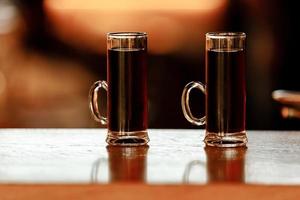 due bicchieri di bicchierini alcolici al bar. mini tiratori di cocktail su sfondo di legno.
