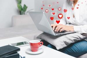 vicino su giovane donna sedersi su divano a casa e utilizzando il computer portatile mentre uso in linea incontri applicazione per saluto e parlare con altro per appuntamenti per flirtare per sociale media stile di vita persone concetto foto