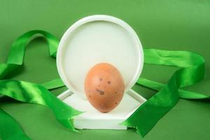 pollo uova su bianca podio con verde nastro su verde sfondo. foto