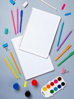 superiore Visualizza preparativi con bloc notes con bianca lenzuola e penne, matite, carta clip e altro ufficio forniture su blu sfondo foto