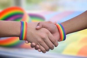 avvicinamento Visualizza di stretta di mano di lgbt persone con sfocato arcobaleno sfondo, concetto per successo, cooperazione, riconciliazione, fiducia, e amore per lgbt persone e celebrazioni nel orgoglio mese. foto