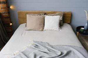 un' moderno scandinavo grigio Camera da letto con colori pastello biancheria da letto e cuscini. di legno letto foto