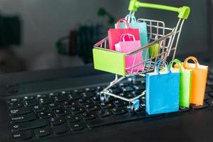 sacchetti di carta colorata nel carrello sulla tastiera di un computer portatile. acquisti in linea da siti tramite il concetto di Internet. foto