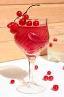 gelatina di vino rosa champagne con ribes rosso in un bicchiere, luce del giorno, su fondo bianco e legno foto