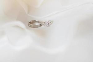 argento e diamante anelli di sposo e sposa su un' bianca stoffa nel nozze giorno. san valentino giorno e amore per celebrazione concetto. foto