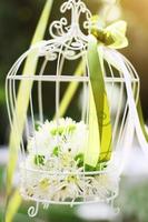 bianca gabbia per uccelli decorazione con Rose e bianca fiori sospeso decorazione nel giardino per nozze cerimonia foto