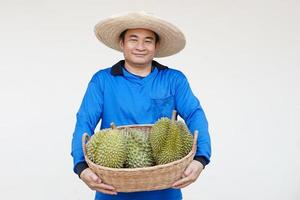 bello asiatico uomo contadino indossa cappello, blu camicia, detiene cestino di durian frutta. concetto, agricoltura occupazione. tailandese agricoltori crescere durian frutta come economico e esportare frutta produzione foto