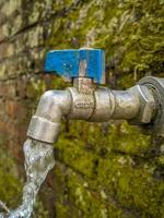 magelang, Indonesia 5 aprile 2023 - in esecuzione acqua rubinetto contro vecchio mattone parete sfondo foto