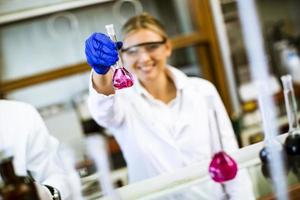 giovane scienziato femminile esaminando liquido nel laboratorio biochimico foto