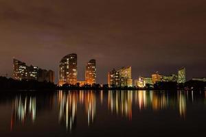 notte città con riflessione di case nel il fiume foto