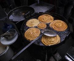 delizioso stizzoso dolce jalebi fritte nel il cucinando padella su un' strada cibo mercato nel chakbazar, dacca-bangladesh foto