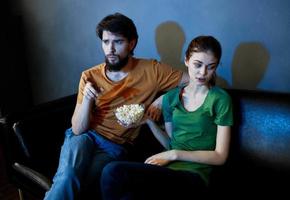 un' donna e un' uomo con Popcorn su un' pelle divano in casa Guardando tv nel il sera foto