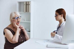 vecchio donna paziente parlando per un' medico stetoscopio foto