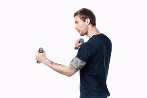 atleta con manubri è impegnato nel fitness su un' leggero sfondo in casa lato Visualizza foto