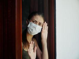 donna nel medico maschera guardare su il finestra lockdown bandire foto