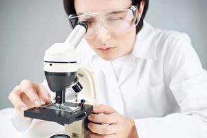 donna nel laboratorio guardare attraverso microscopio avvicinamento biotecnologia scienza foto