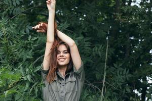 donna nel il foresta detiene il suo mani sopra il suo testa verde le foglie foto