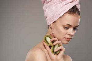 donna con rosa asciugamano su sua testa spoglio le spalle ritagliata Visualizza di Kiwi frutta nel Salute mano foto