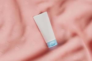 barattolo di crema cosmetica bianco con coperchio blu su tessuto rugoso rosa, rendering 3d