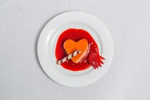 cuore sagomato budino con fragola salsa e wafer. san valentino dolce ricetta. foto