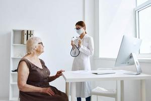 anziano donna indossare un' medico maschera comunica con il medico Salute cura foto