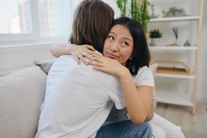 un' uomo abbracci il suo asiatico donna amico a casa. psicologico supporto per un' amico foto
