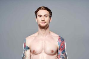 allegro uomo con un gonfiato muscolare corpo tatuaggio su il suo braccia in posa foto