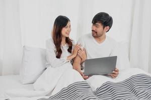 giovane contento asiatico coppia utilizzando il computer portatile nel letto Guardando film, romantico tempo per migliorare famiglia relazione, famiglia concetto. foto