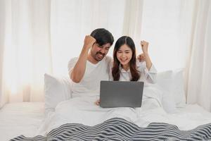 giovane contento asiatico coppia utilizzando il computer portatile nel letto Guardando film, romantico tempo per migliorare famiglia relazione, famiglia concetto. foto