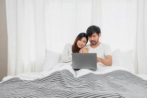 giovane contento asiatico coppia utilizzando il computer portatile nel letto Guardando film, romantico tempo per migliorare famiglia relazione, famiglia concetto. foto