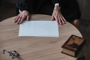 il mani di un' giovane donna hold un' vuoto foglio di carta su un' di legno tavolo. modello, copia spazio foto