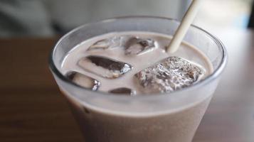 un' bicchiere di ghiaccio cioccolato latte a un' tavolo con un' cannuccia. foto