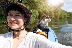 uomo e donna coppia, bambino è dormendo, selfie siamo contento nel famiglia kayak viaggio canottaggio barca su il fiume, acqua escursione, un' estate avventura. eco-friendly e estremo turismo, attivo e salutare stile di vita foto