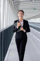 giovane asiatico donna d'affari nel nero completo da uomo utilizzando digitale tavoletta e in piedi su passerella stazione con copia spazio. foto