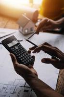 costruzione e struttura concetto di ingegnere o architetto incontro per progetto Lavorando con compagno e ingegneria utensili su modello edificio e planimetria nel Lavorando luogo, contrarre per tutti e due aziende. foto