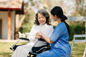 asiatico femmina mani toccante vecchio femmina mano porzione mani prendere cura di il anziano concetto nel parco ospedale foto