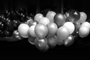 un' mazzo di colorato pieno di gas palloncini su buio sfondo. nero e bianca Immagine. foto