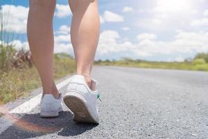 donna che cammina sulla piccola strada di campagna con lo sfondo del cielo blu foto